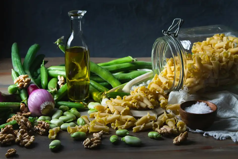 Bodegón de pasta, aceite de oliva y verduras sobre madera