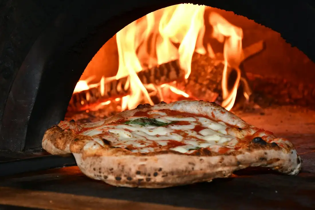 Pizza napolitana saliendo del horno de leña