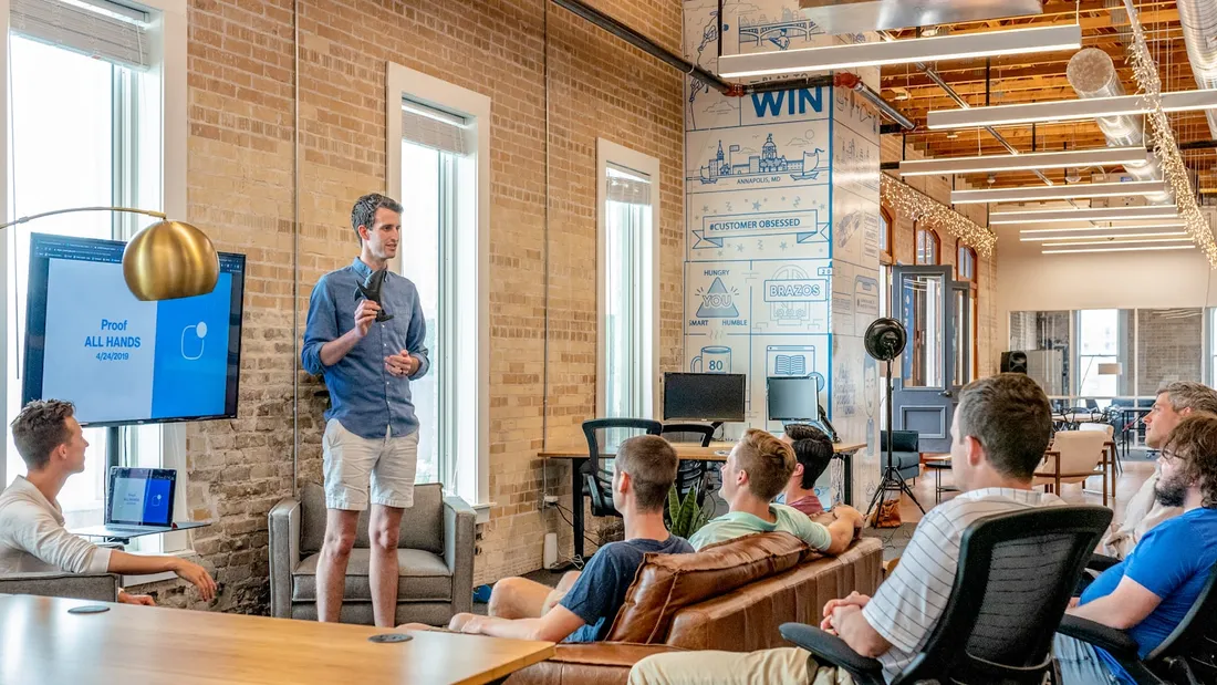 A person explains something to a team in front of a screen: how AI assistants answer