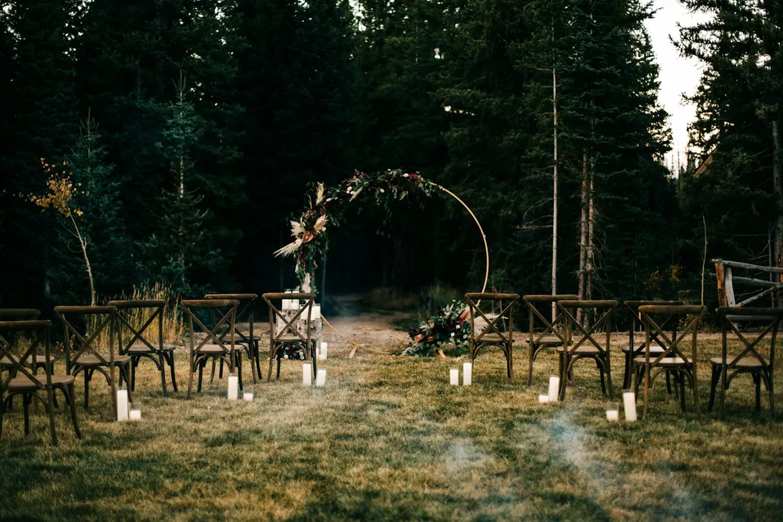 Outdoor ceremony with chairs and a flower arch at dusk