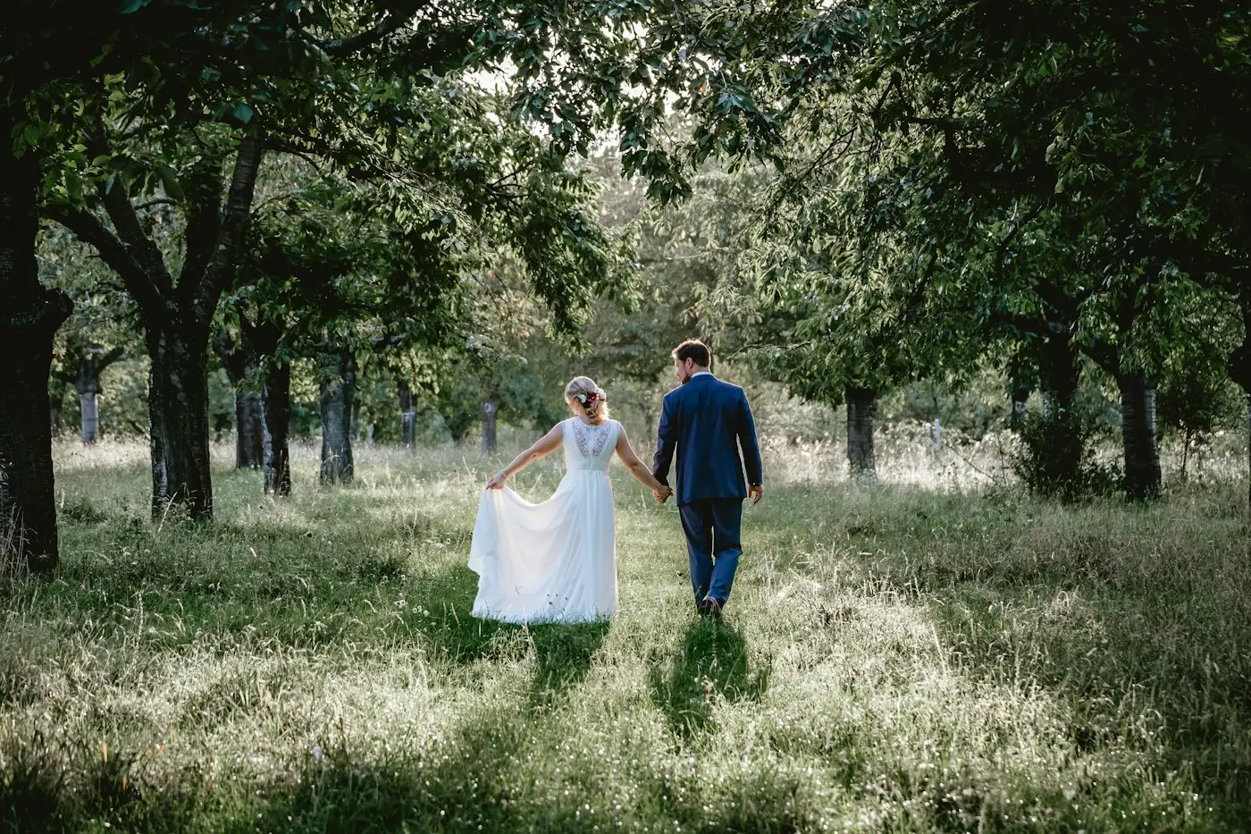 Los novios de espaldas caminando por el jardín